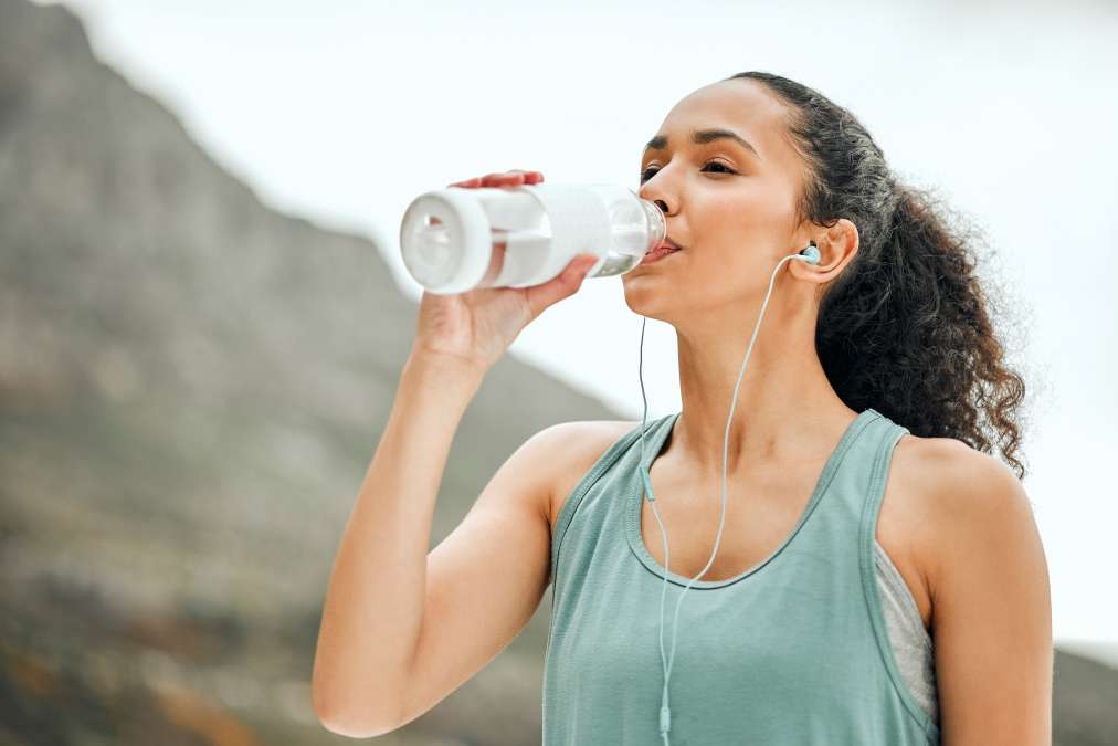 A WOMAN WORKING OUT AND DRINKING WATER