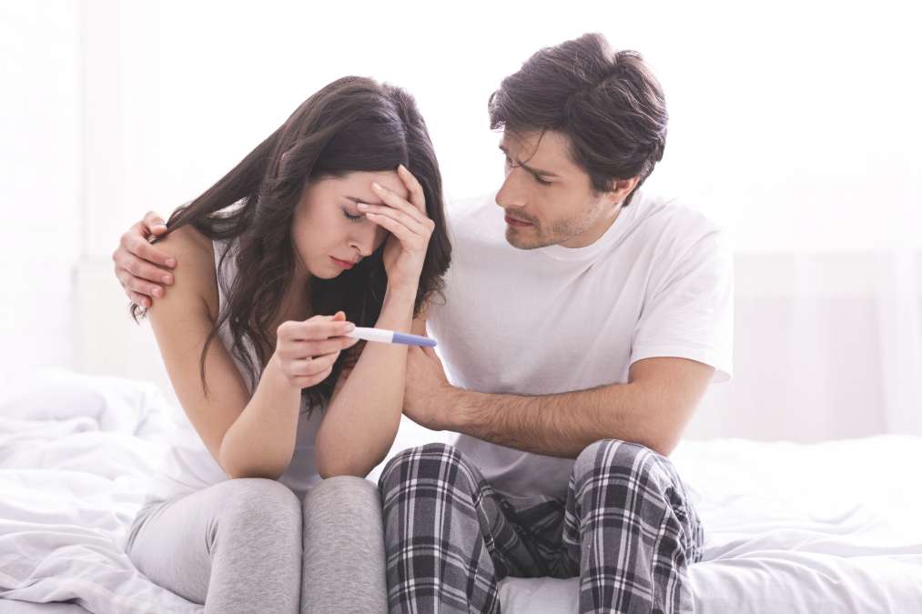 Man comforting his wife with negative pregnancy test
