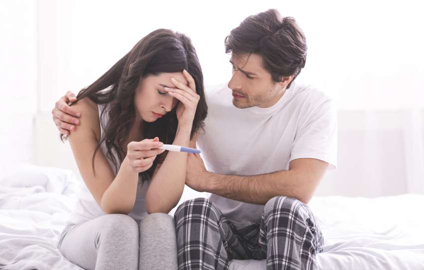 Man comforting his wife with negative pregnancy test