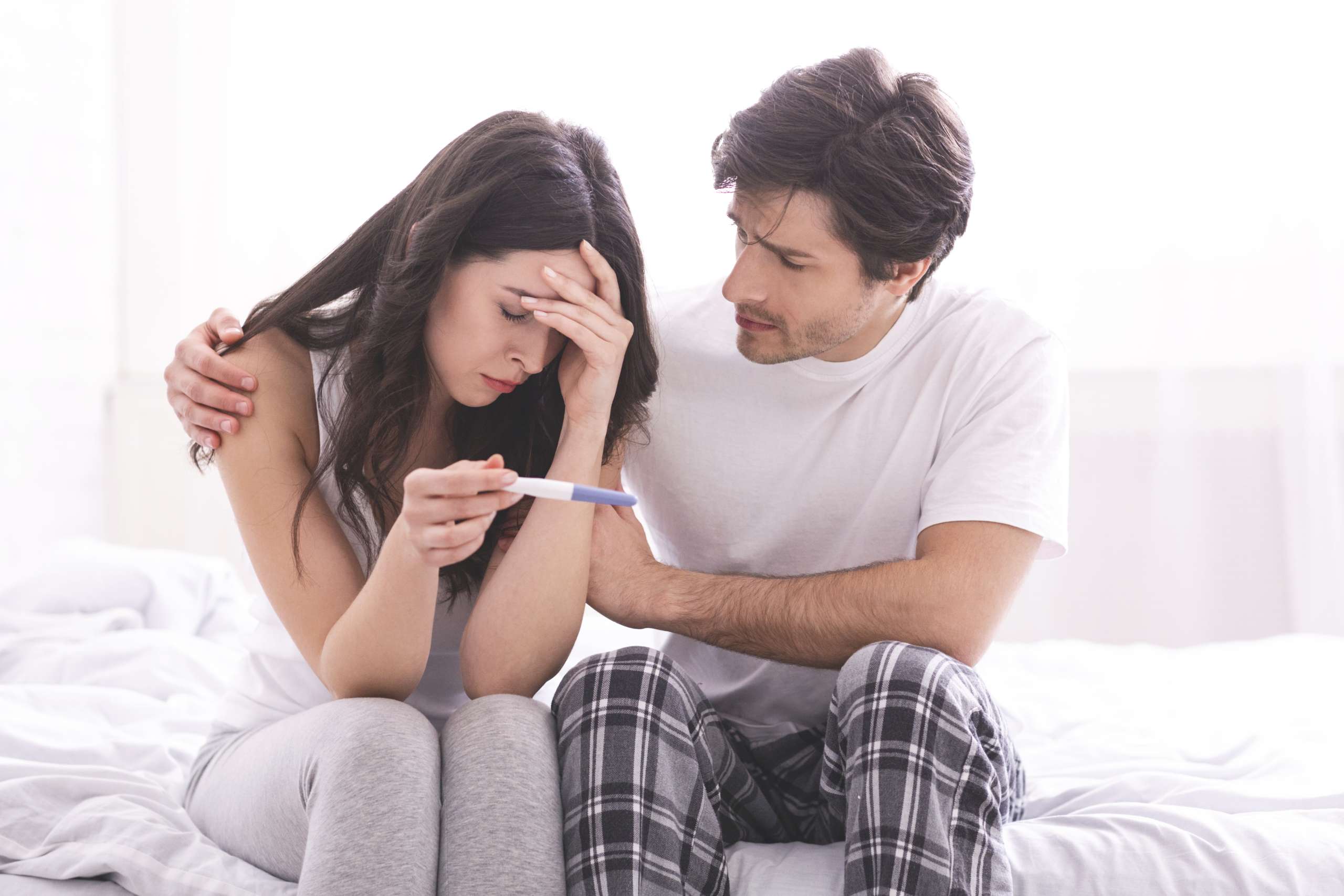 Man comforting his wife with negative pregnancy test- Anxiety Related To Fertility