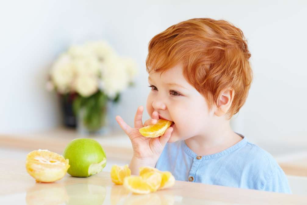 toddler baby tasting orange slices