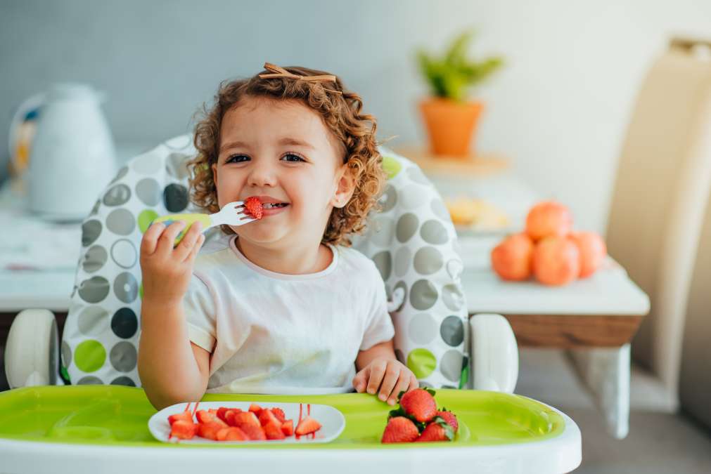 Child eating strawberry for breakfast
