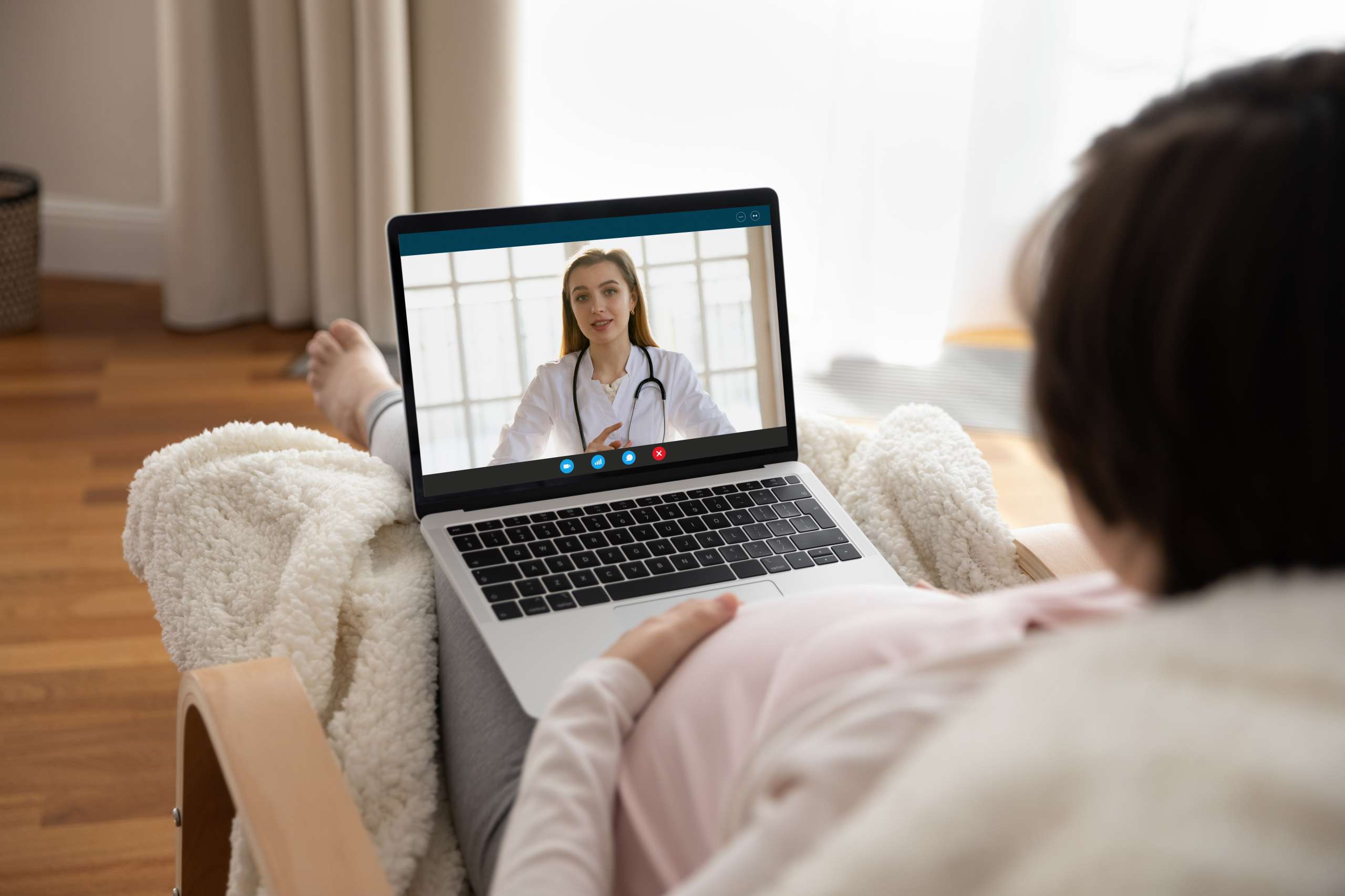 Young pregnant woman talk to doctor by videocall using laptop