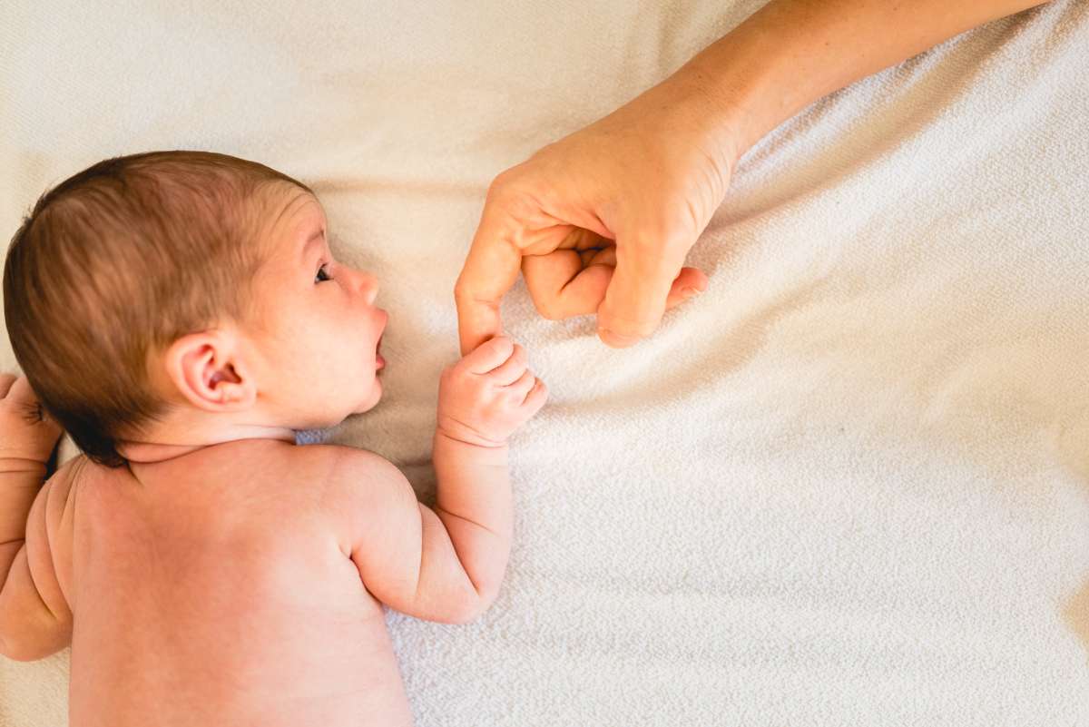 newborn holding mother's finger