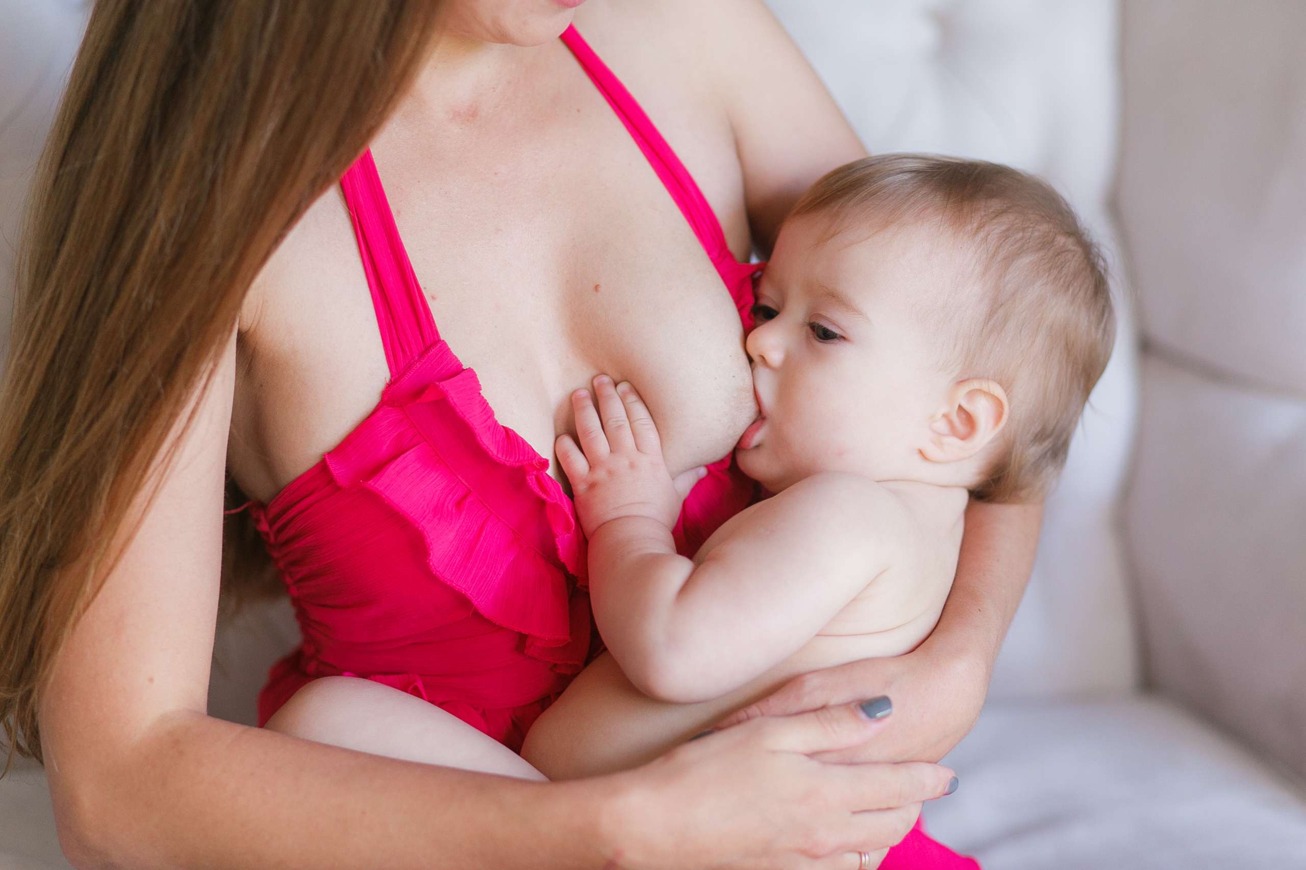 Young woman breastfeeding her little baby at home, closeup. Wearing pink dress-Menstrual Regularity