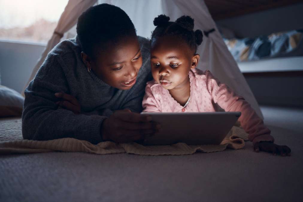 mother helping child study using tab