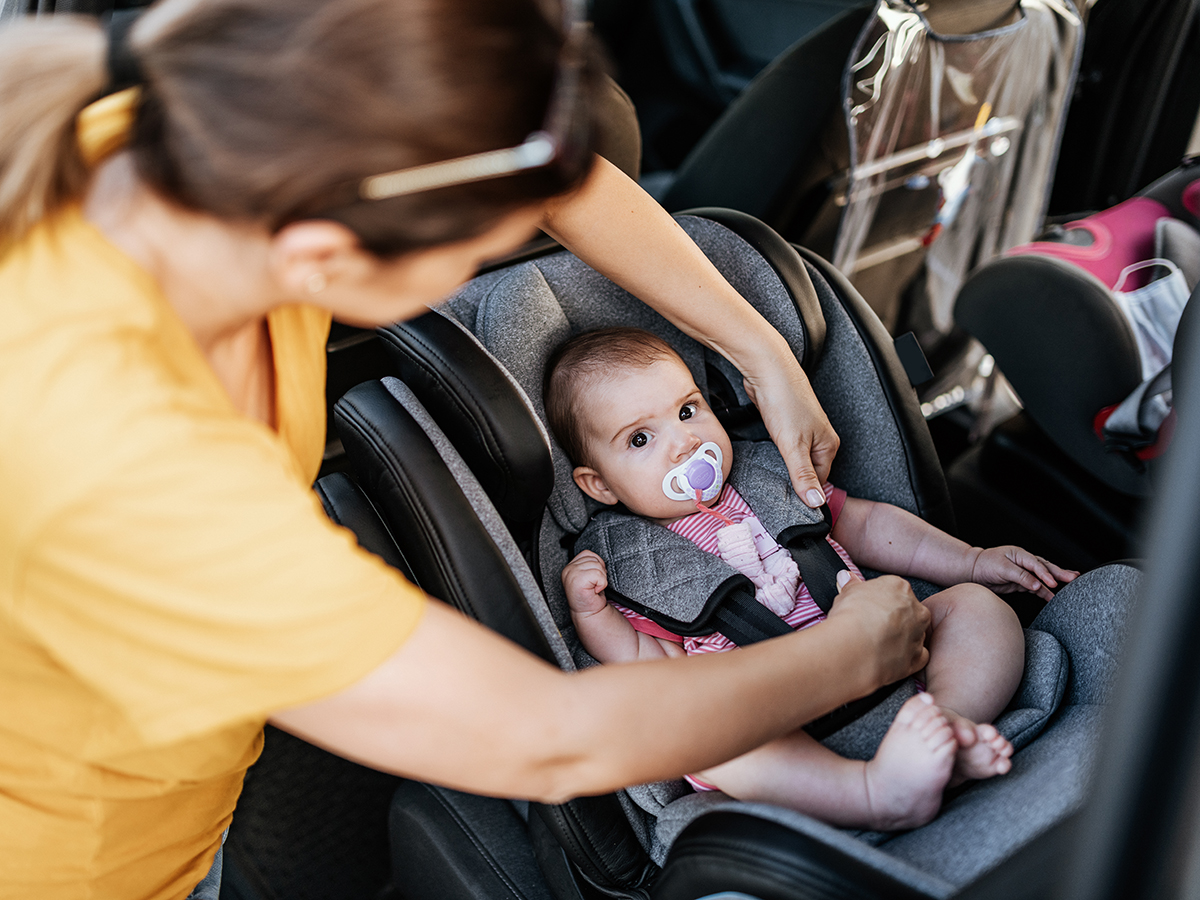 MOTHER BUCKLING THE CHILD IN CAR SEAT