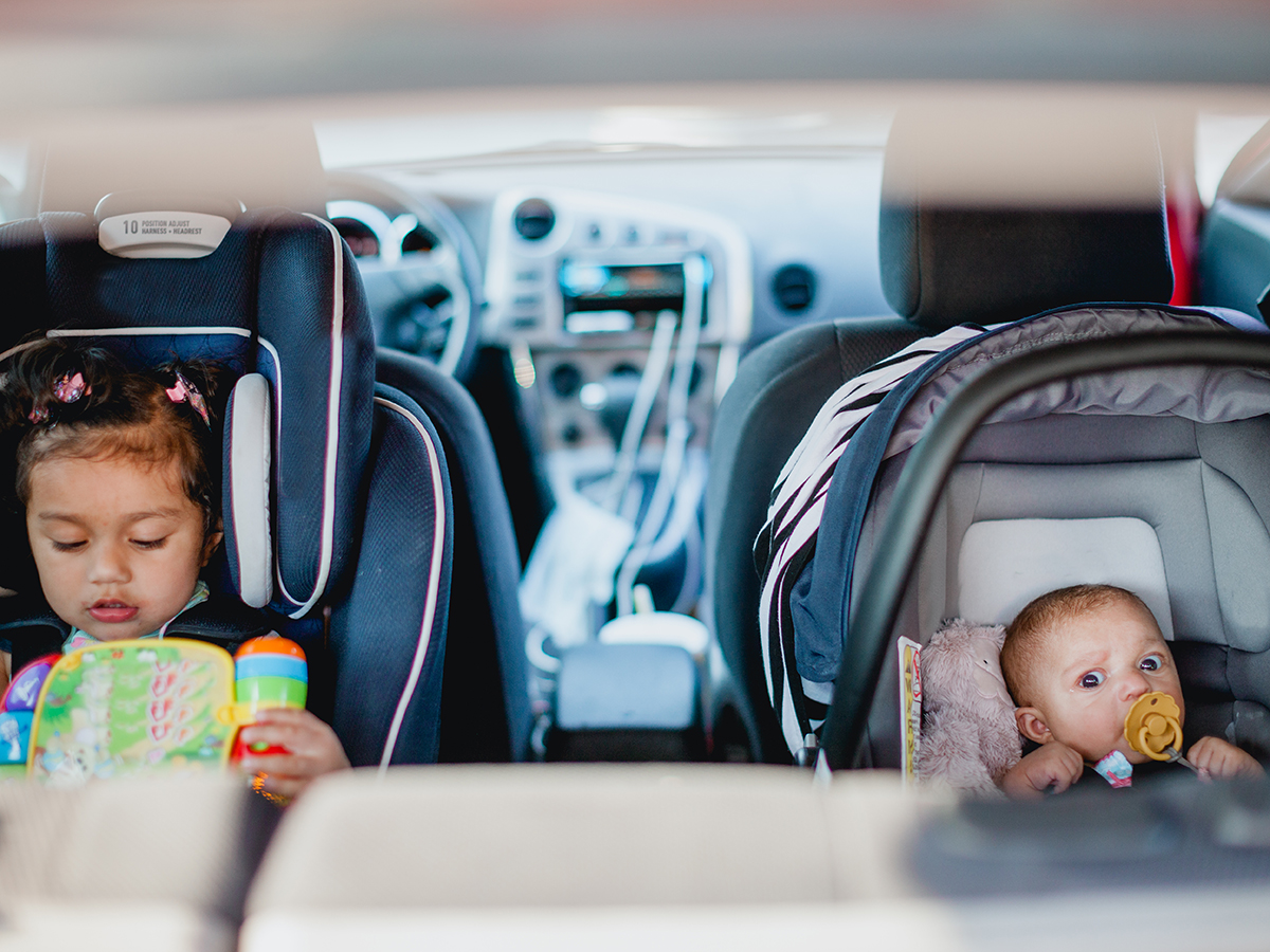 TWO CHILDREN IN DIFFERENT SIZED CAR SEATS