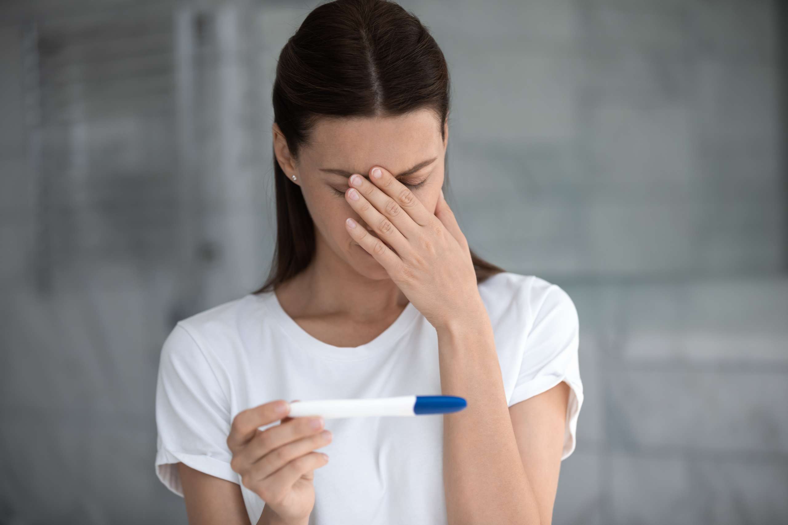 Upset woman looking at pregnancy test bad result feels disappointed