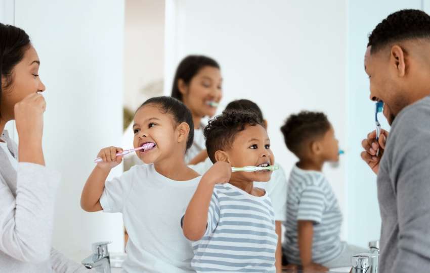 toddlers brushing teeth with parents
