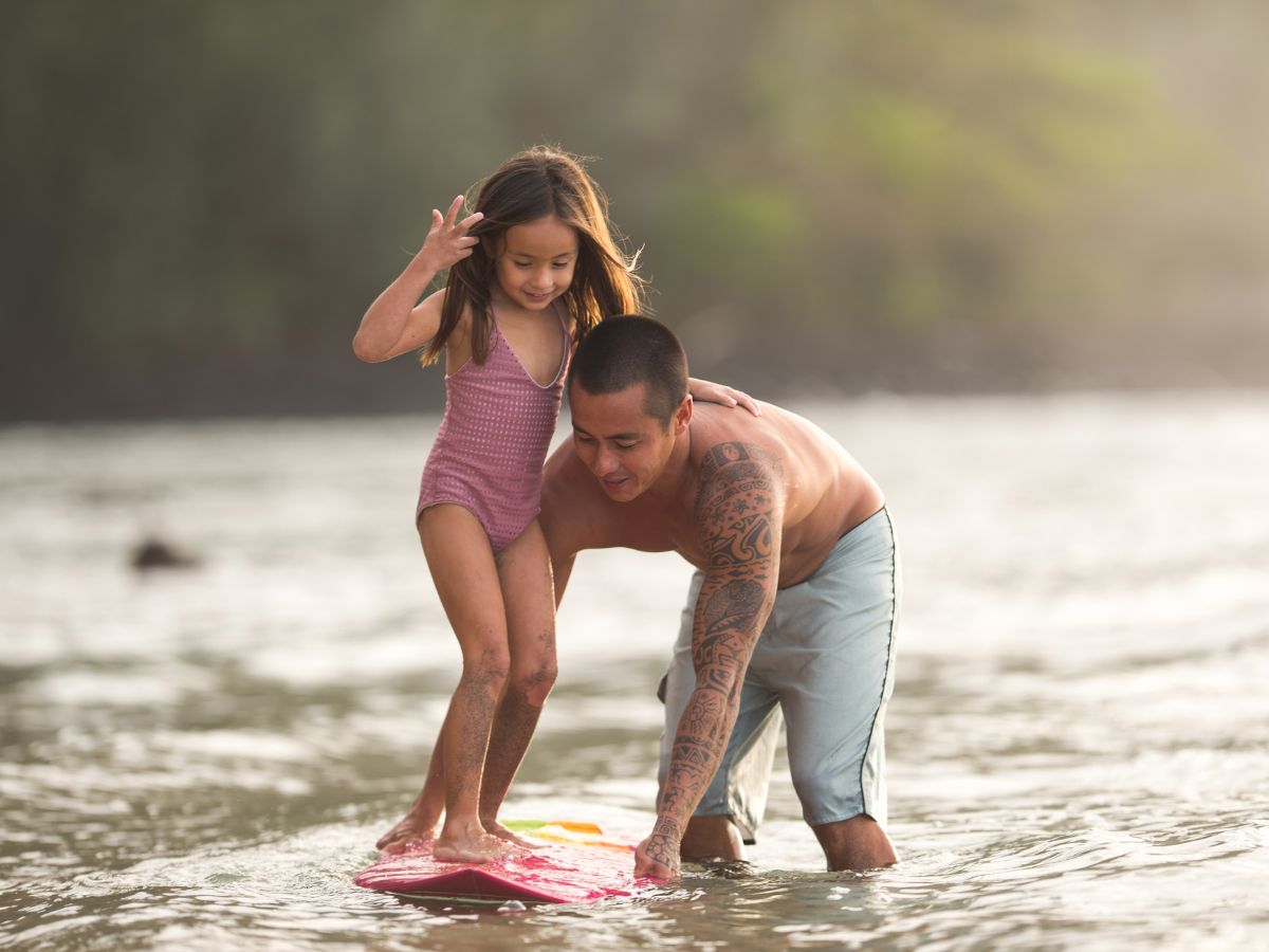 father teaching child to surf