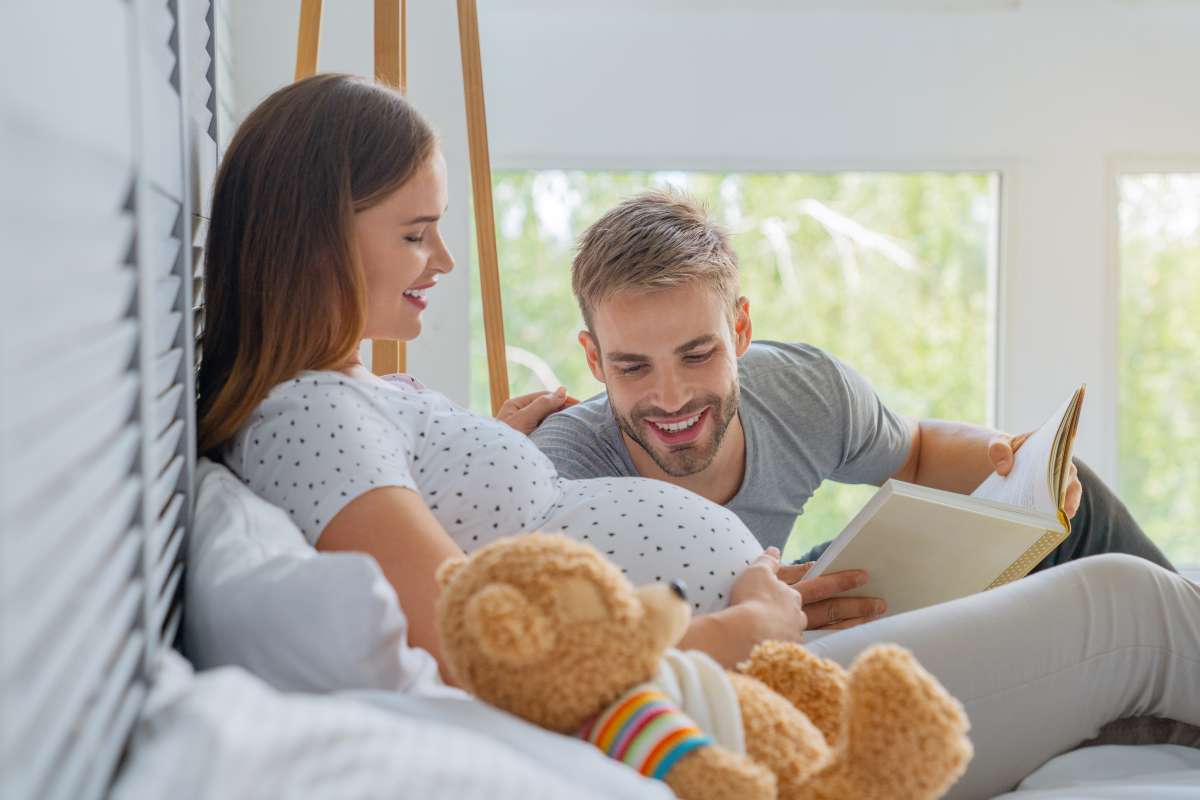 husband reading story to pregnant wife and baby