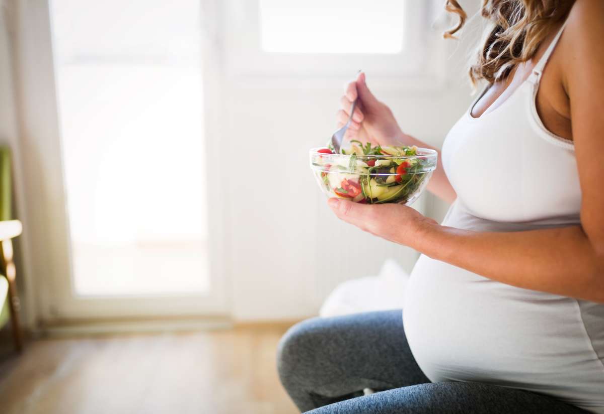 Beautiful pregnant woman eating healthy food and salads-Manage Second Trimester Discomfort