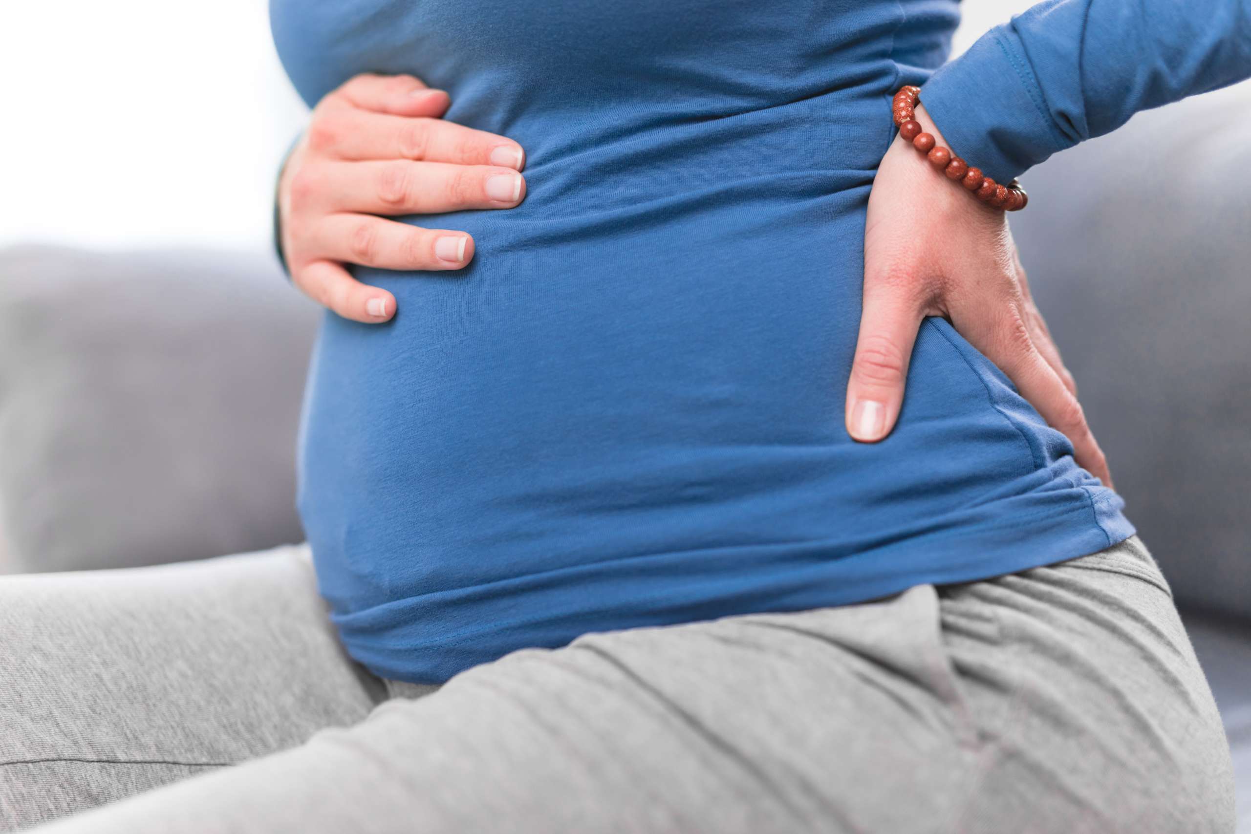 Pregnant tired exhausted woman with stomach issues and back pain at home on a couch, being sick- Maternal Obesity