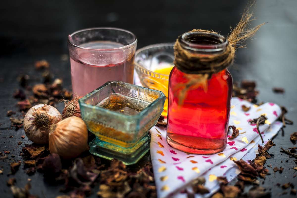 Home remedy for hair fall on wooden surface in glass bowl well mixed with ingredients as rose water, raw onion juice and honey