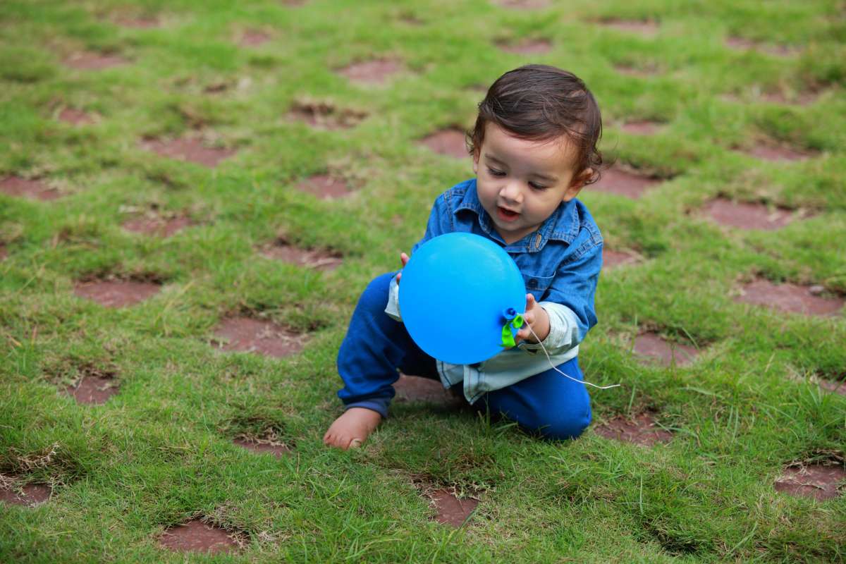 Toddler plays with an inflated balloon ball in the outdoor