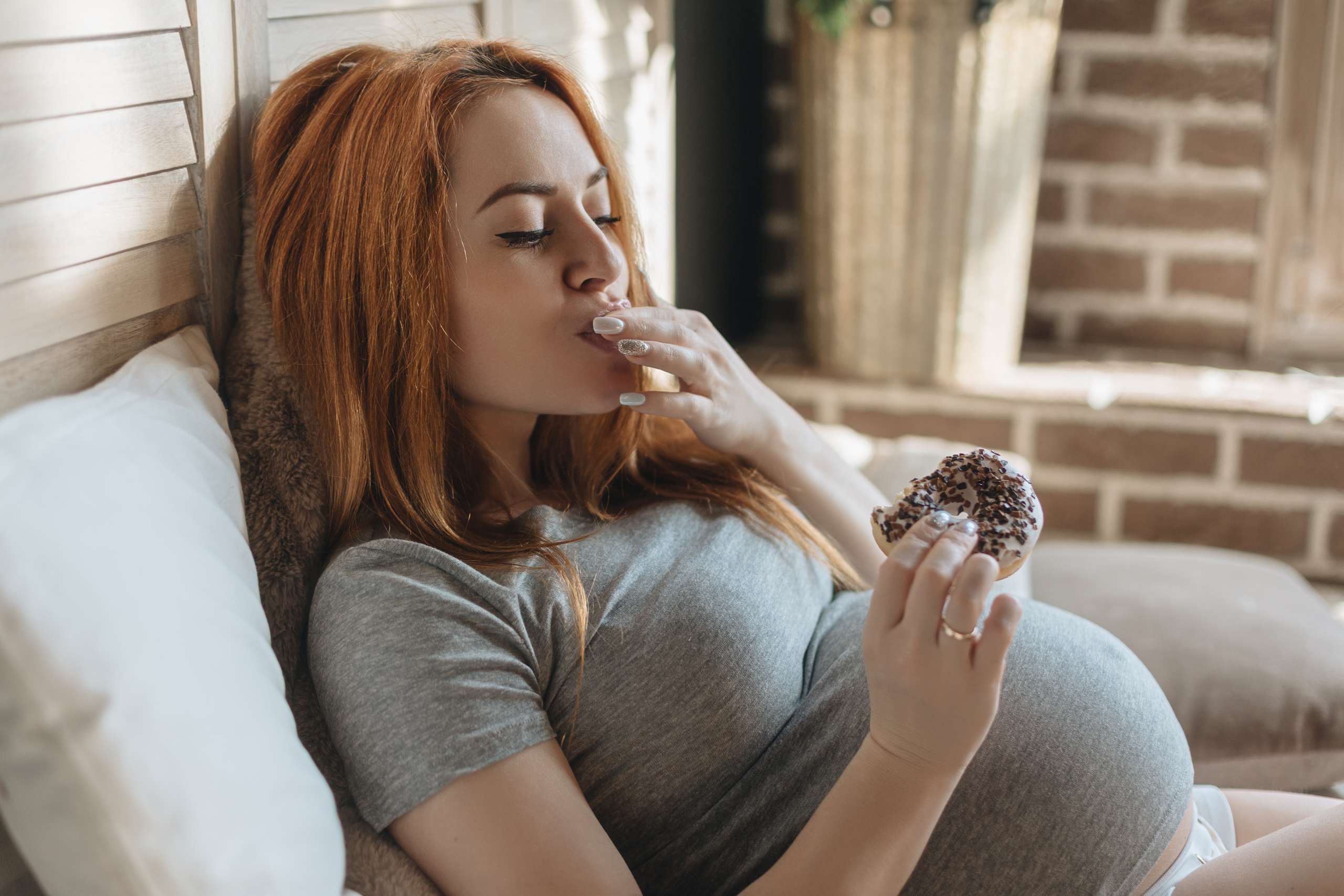 Pregnant woman eating tasty donuts