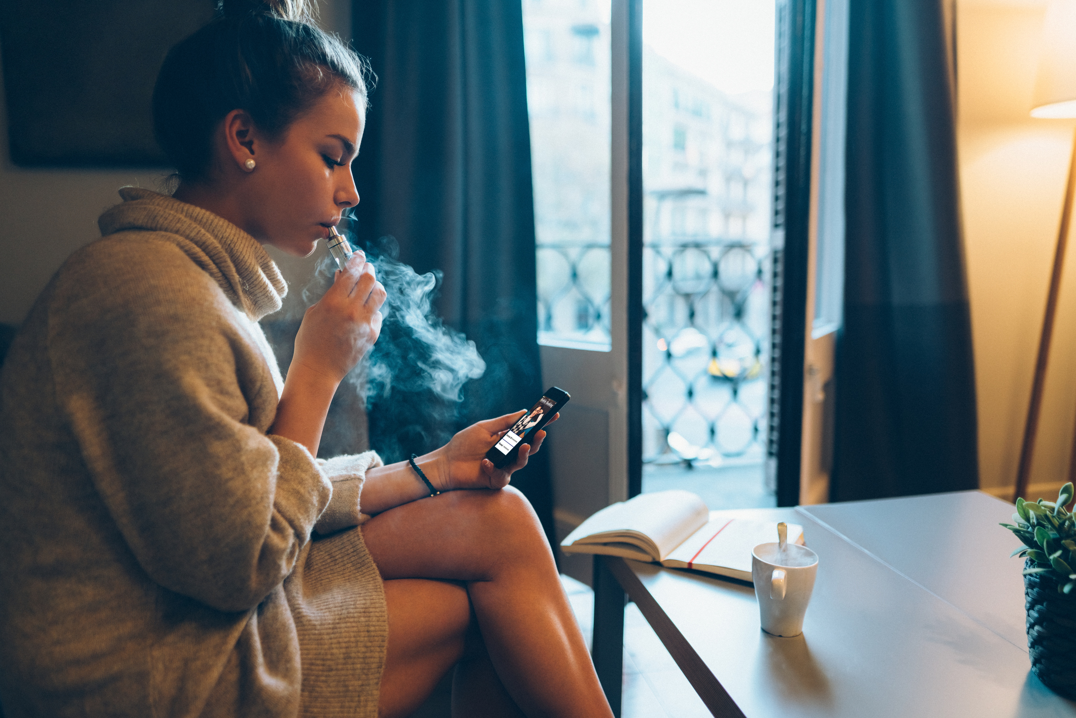 Young girl at home smoking electronic cigarette