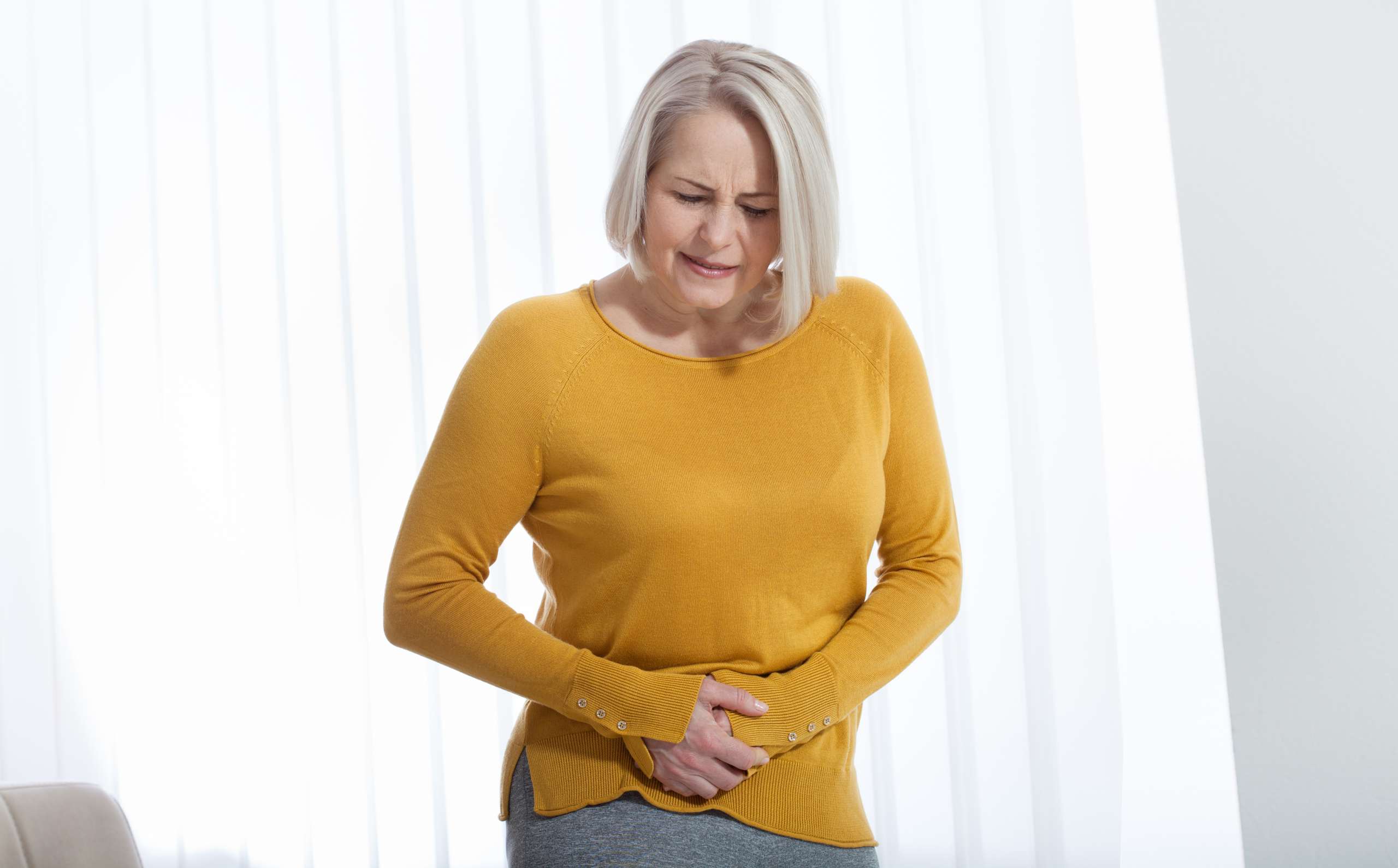Middle aged woman suffering from abdominal pain while at home- Advanced Maternal Age Complications 