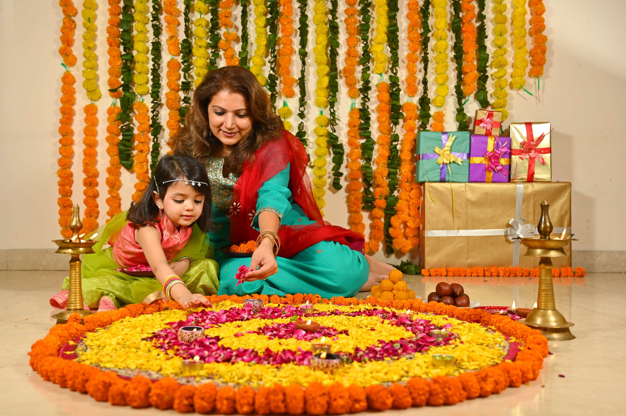 Mother and daughter decorating flower rangoli on the floor