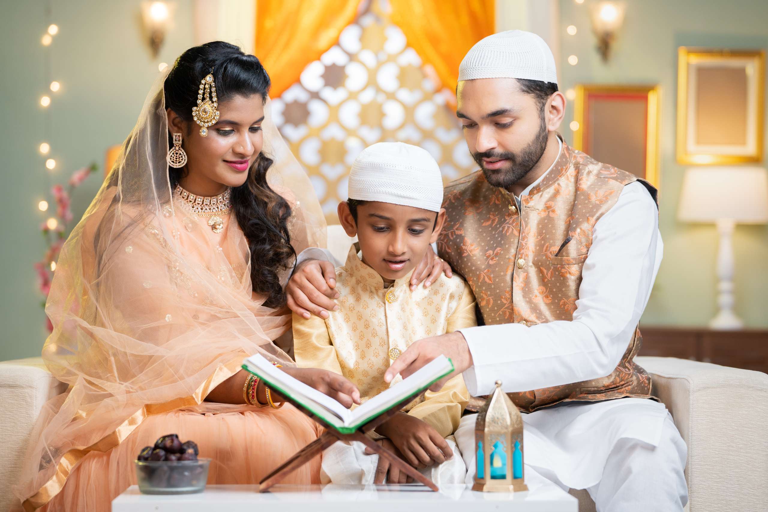 Indian Muslim parents helping kid to reading Quran before fasting food during Ramadan festival at home - concept of festival ,supportive family and bonding-Family Traditions In Child's Identity Formation