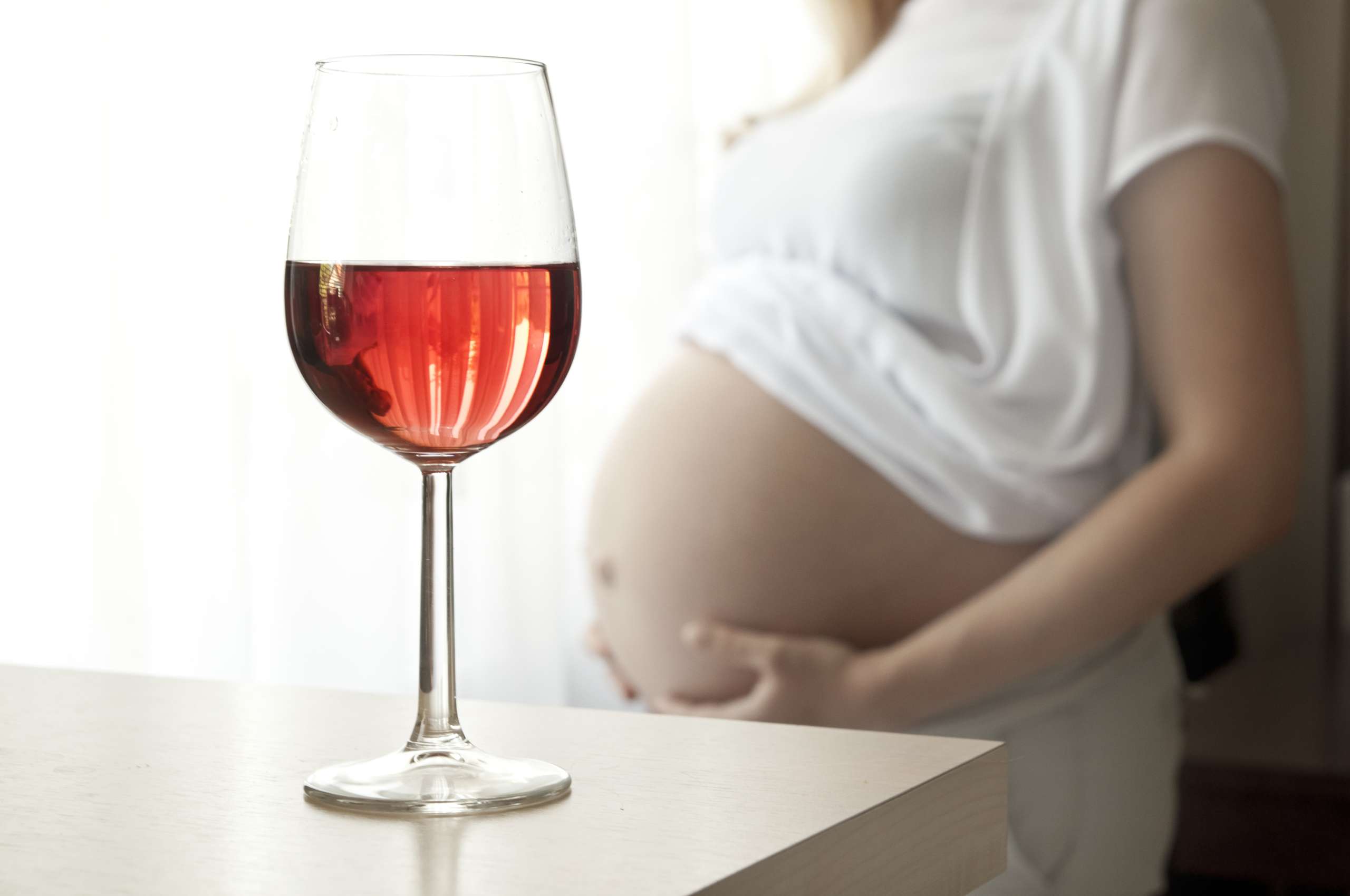 Pregnant woman and a glass of wine - drinking mother, social problems- Maternal Drug Use