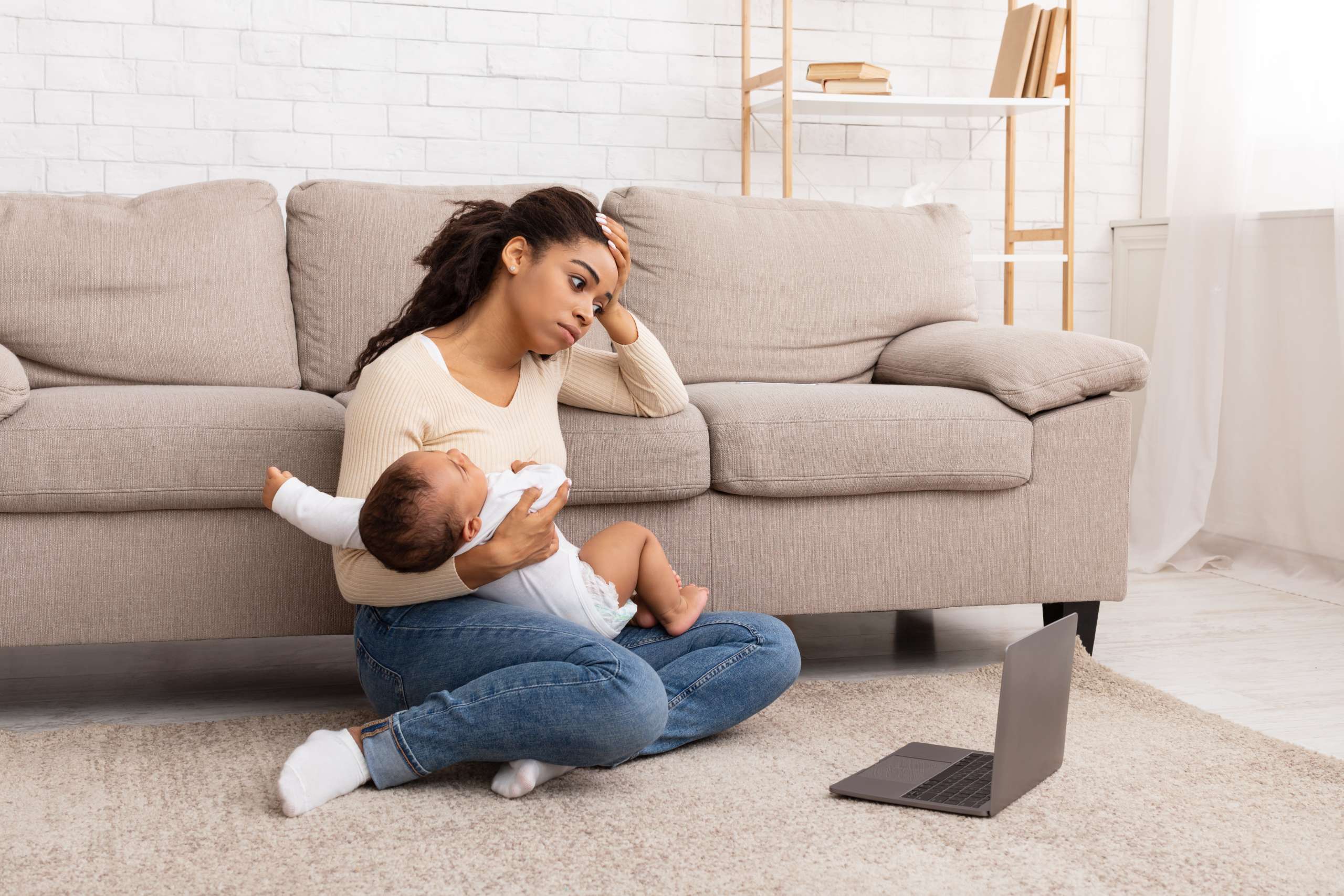 Exhausted Black Mother Holding Crying Baby Sitting At Laptop Indoor