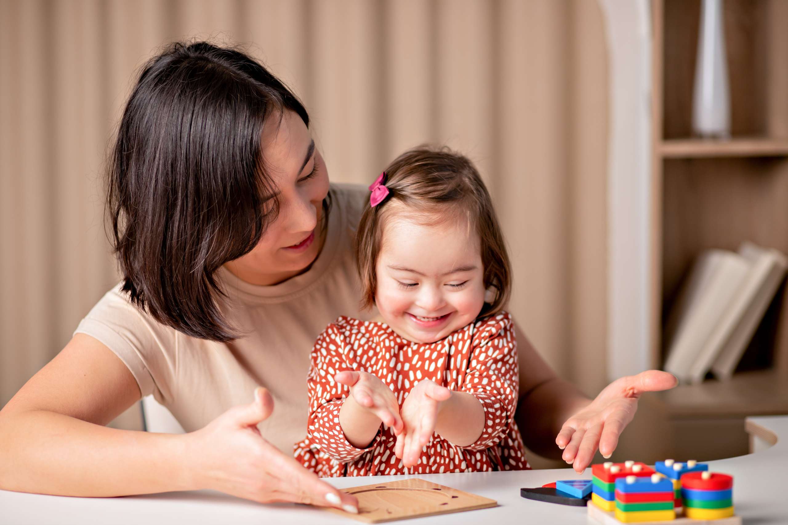 child with down syndrome with educational toys smiles, a cute girl with her mother a teacher-Down Syndrome On Expectant Mothers