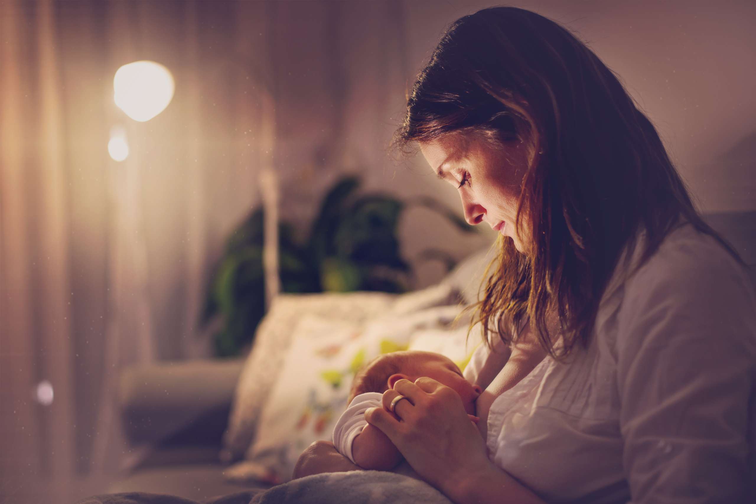 Young beautiful mother, breastfeeding her newborn baby boy at night-Menstrual Regularity